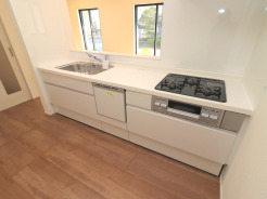 【Kitchen】
食洗器搭載システムキッチン。清潔感あふれる白で統一された空間が、心地よい暮らしを予感させます。窓の外の緑が、室内に柔らかな彩りを添え、穏やかなひとときを演出します。