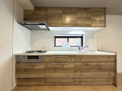 【Kitchen】
温かみのある木目調の扉が、空間に穏やかな表情を与えています。作業スペースを照らす照明は、心地よい明るさを保ちながら、清潔感のあるキッチンを演出します。